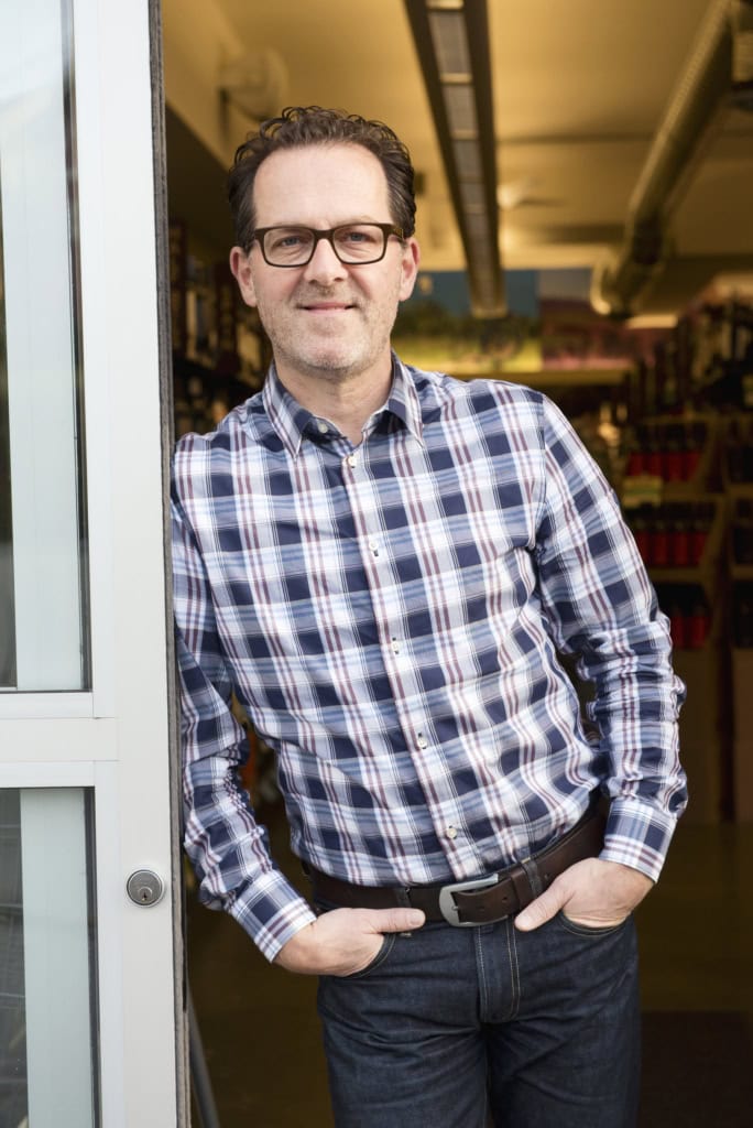 Smiling man leaning casually against white doorway