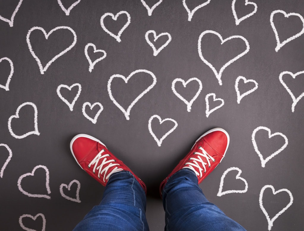 Red shoes, standing on a dark sidewalk covered in white chalked hearts.