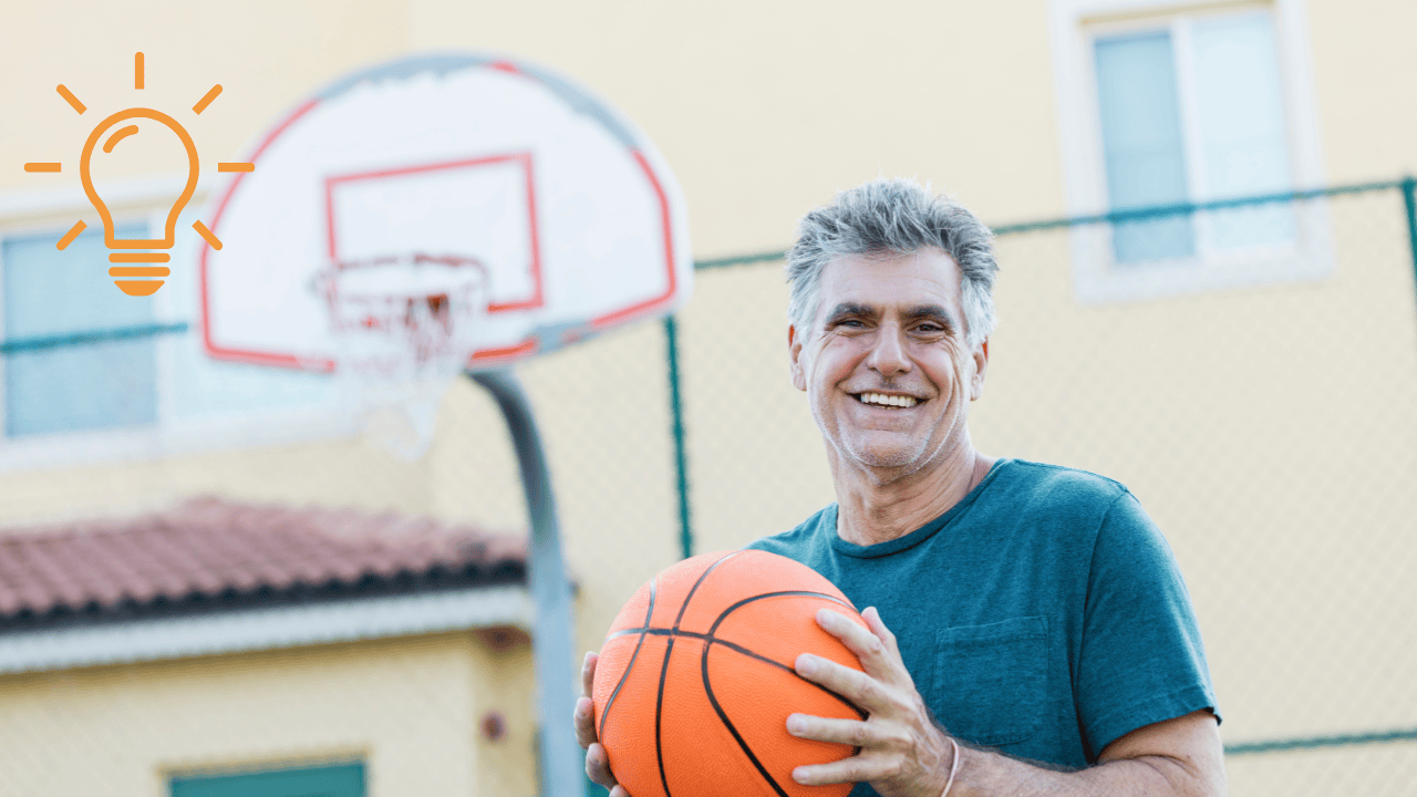 healthy middle aged man holding a basketball looking relaxed and happy