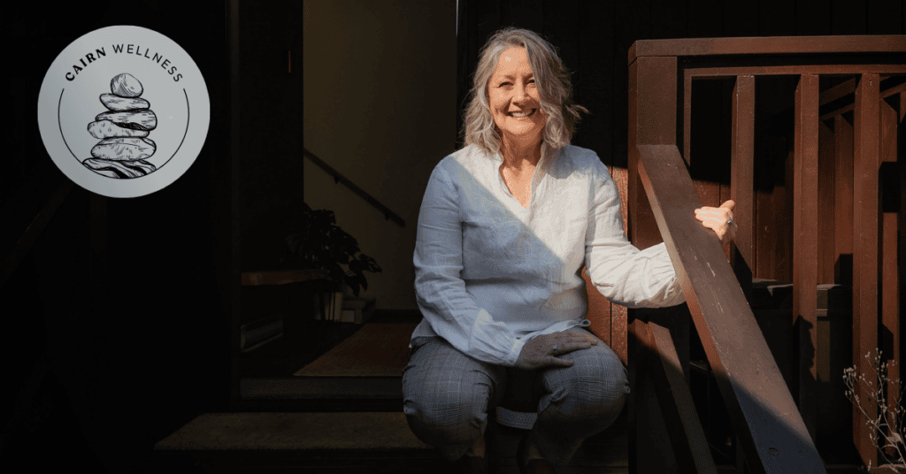 Smiling, peaceful woman sitting on wooden steps, haloed in sunlight.