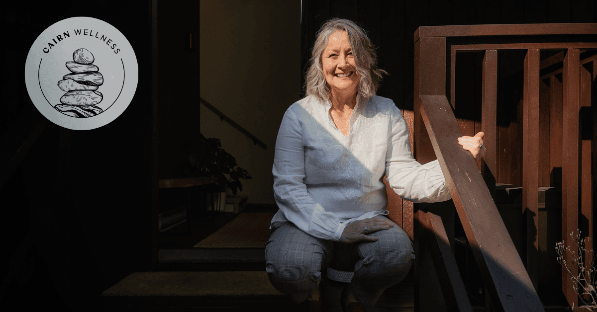 Smiling, peaceful woman sitting on wooden steps, haloed in sunlight.